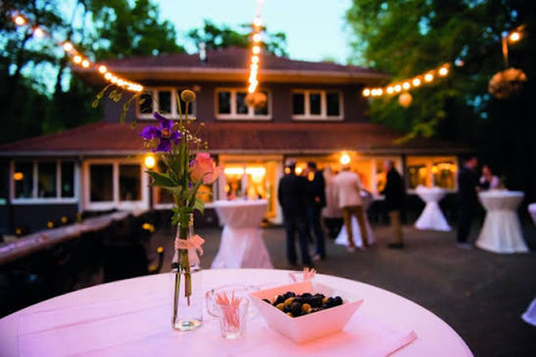 Terras van 't Paviljoen bij valavond, met lichtslingers en statafels