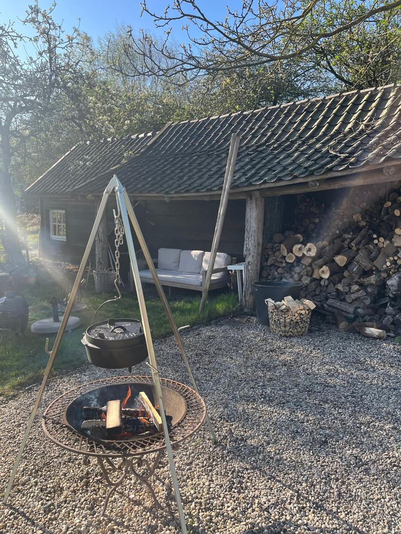 Gietijzeren pot boven een houtvuur op een driepoot